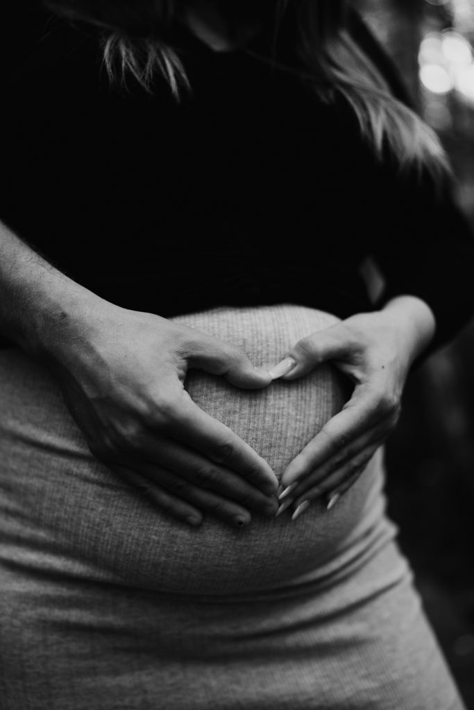 Schwangere Frau macht Herz vor dem Bauch.