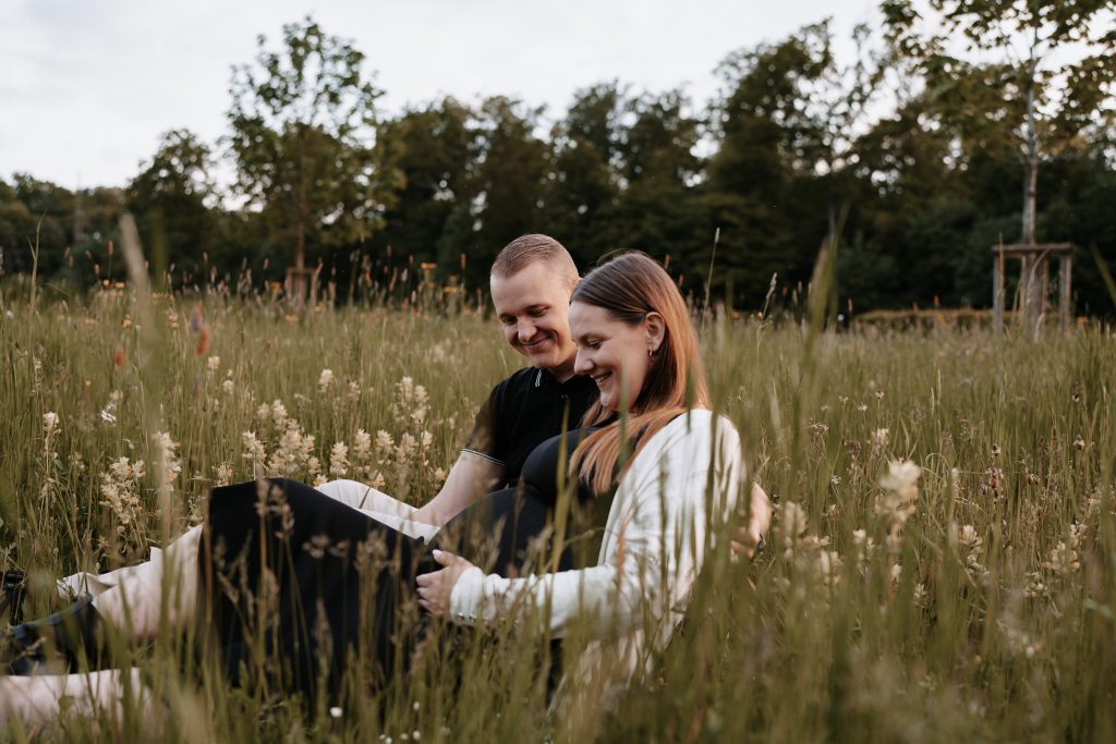 Brautpaar, die zu Eltern werden auf einer Wiese.