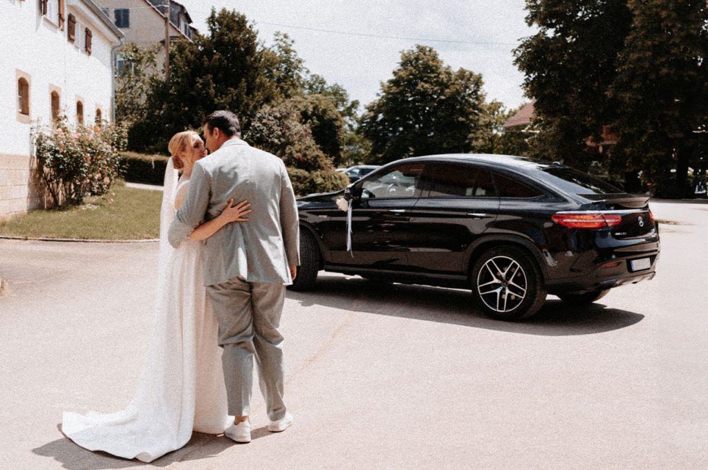 Brautpaar vor einem schwarzen Auto. Goldenphotos by Ana Schmauder Hochzeits fotografie